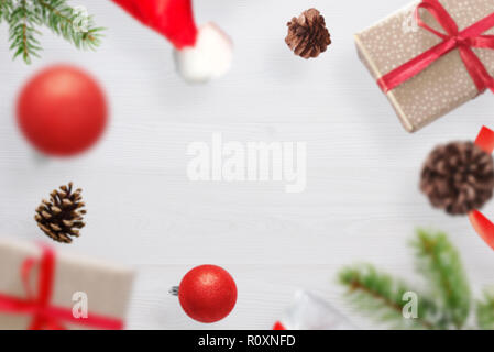 Christmas gifts, fir branches, Santa Claus's hat and cones fall on a white wooden table. Fre space for text. Stock Photo