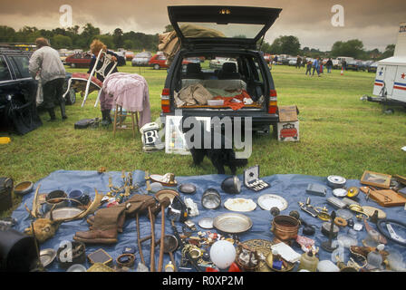 Car boot sale junk, including old boots, plates and car headlamps, laid out on display for sale on a groundsheet in a showground field in Berkshire Stock Photo