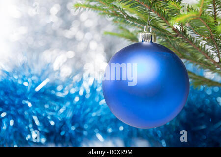 Christmas decorations, one blue ball hanging on Christmas tree on a background of tinsel foil Stock Photo