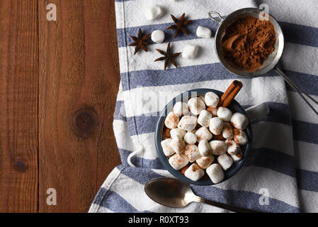 A mug of hot cocoa on a kitchen towel and rustic wood table with copy space. Stock Photo
