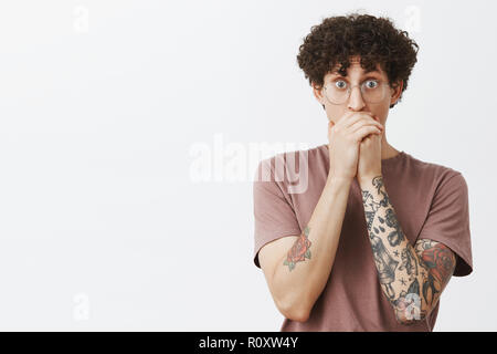 Man seeing friend making cool trick on skate gasping staring amazed and surprised covering mouth with hands popping eyes at camera standing impressed and shocked over gray background Stock Photo