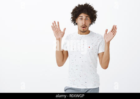 Excited and emotive handsome male describing huge boom happened on street. Portrait of good-looking surprised and shook hispanic man with moustache gesturing with raised palms while talking Stock Photo