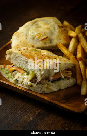 Grilled chicken panini with fresh crispy steak fries on rustic wooden kitchen table Stock Photo