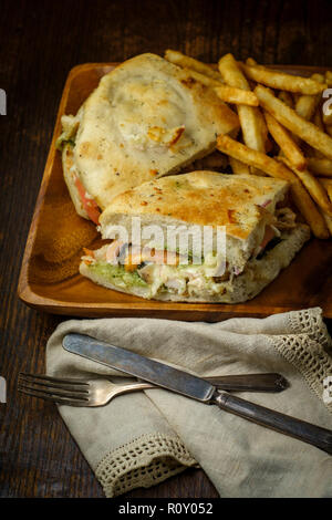 Grilled chicken panini with fresh crispy steak fries on rustic wooden kitchen table Stock Photo