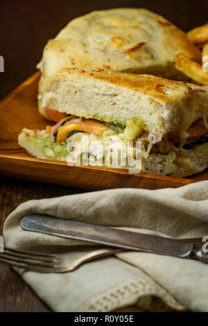 Grilled chicken panini with fresh crispy steak fries on rustic wooden kitchen table Stock Photo