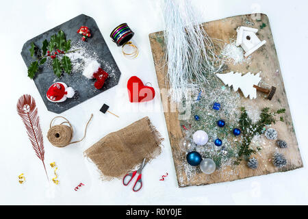 Accessories, Preparing for Christmas. Holiday background decoration toys, garlands, on a old wooden board and a slate squrare wreath over old wite ,top view Stock Photo