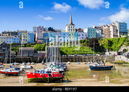 Low tide at Tenby, Pembrokeshire, Wales, United Kingdom. Sailing boats and yachts beached against the painted terraced houses and church. Seaside town Stock Photo