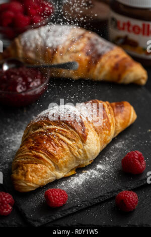 Freshly baked croissants with nutella on a white plate near