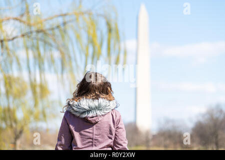 Closeup of young female, woman back looking at view on Washington Monument with willow tree branches, green leaves, foliage in spring, blue sky Stock Photo