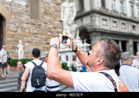 Florence, Italy - August 30, 2018: Man taking pictures of ancient, antique, medieval architecture in Firenze at Piazza della Signoria, square with pho Stock Photo