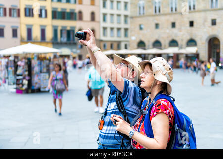 Florence, Italy - August 30, 2018: Couple, man, woman taking picture, photo with camera of ancient, antique, medieval architecture in Firenze at Piazz Stock Photo