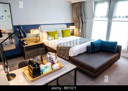 Hotel room with coffee maker in foreground. Coffee is dripping