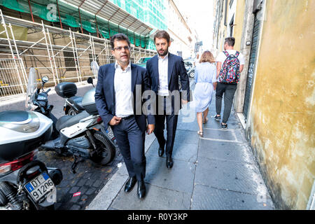 Rome, Italy - September 4, 2018: Two men pedestrians business businessmen walking on sidewalk street road in center of downtown city holding tablet in Stock Photo