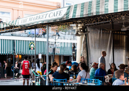 New Orleans, USA - April 22, 2018: People sitting eating cajun creole cuisine food at the Market Cafe restaurant, tables, blue sign on Decatur street