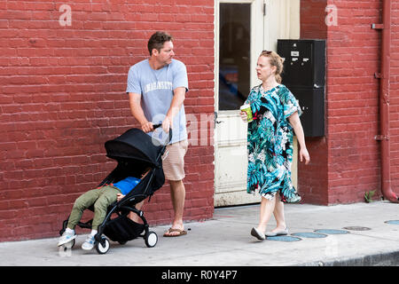 New Orleans, USA - April 22, 2018: Old town street in Louisiana famous city, people tourists couple family talking pushing baby stroller on sidewalk,  Stock Photo