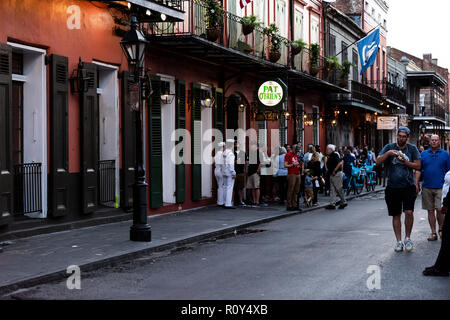 New Orleans, USA - April 22, 2018: Old town St Peter Pierre street in Louisiana town, city, crowd group of people sailors standing by famous Pat O'Bri Stock Photo