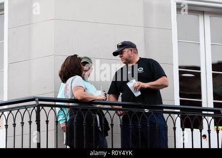 New Orleans, USA - April 22, 2018: Old town Bourbon street in Louisiana town, city, balcony building, people standing drinking beer at bar during even Stock Photo