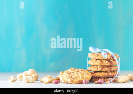 Christmas and New Year composition with delicious peanut cookies and peanuts on light table and blue background. Stock Photo
