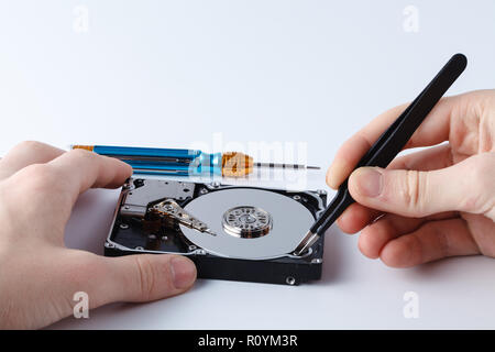 Hard disc drive disassembling close up. Repairman opening hdd for recovery information, service center and electronics repair concept Stock Photo