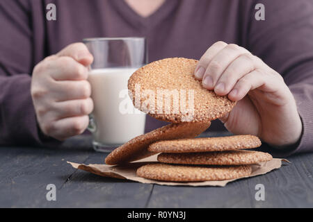 Hands holding cup of coffee and cookies on black background Stock Photo