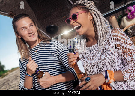 Funny couple traveling with mobile phone opening beer with eyes and teeth Stock Photo