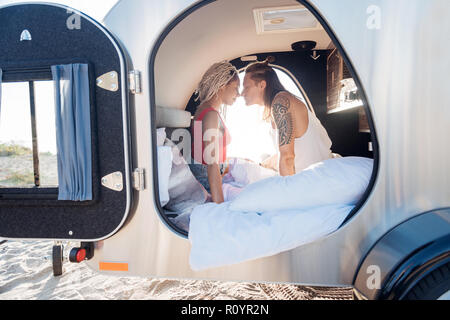 Cute loving couple feeling good waking up in compact trailer together Stock Photo