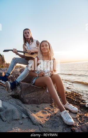 Couple of creative musicians playing their favorite song near the seaside Stock Photo