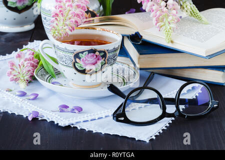 Cup of tea with books and flowers on wooden background Stock Photo