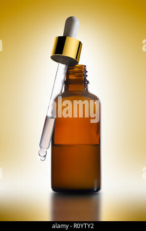Essential beauty treatment in brown dropper bottle with pipette against yellow background, studio still life Stock Photo