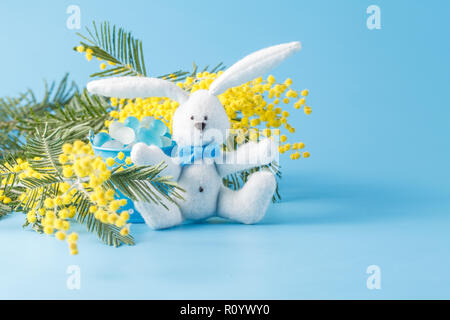 White toy rabbit and yellow mimosa. Spring decoration Stock Photo