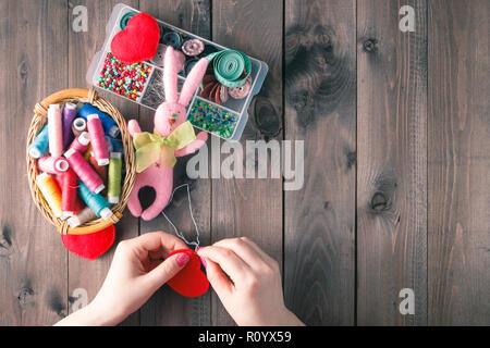 Woman sews red heart shaped toy by needle, top view Stock Photo