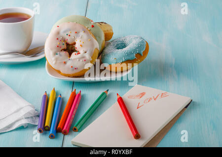 olorful donuts on saucer and sketchbook with painted heart Stock Photo