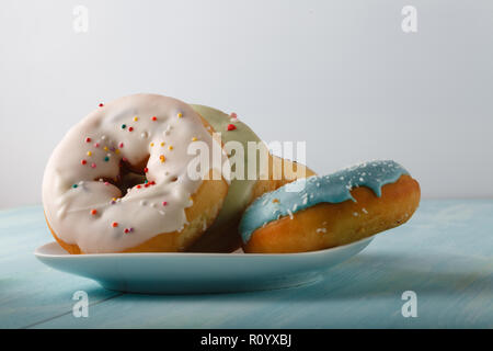 Donuts on white saucer standin on old wood table Stock Photo