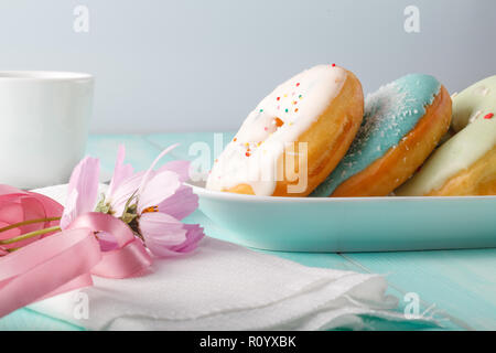 Four donuts on old wood table with flowers Stock Photo