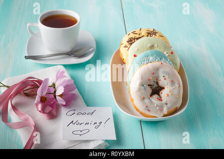 Four donuts on old wood table with flowers on dish Stock Photo