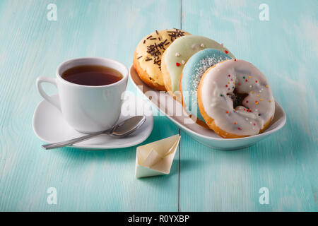 Four donuts on old wood table with cup of tea and origami Stock Photo