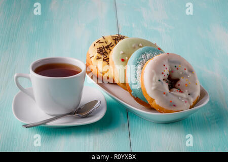 Four donuts on old wood table with cup of tea Stock Photo