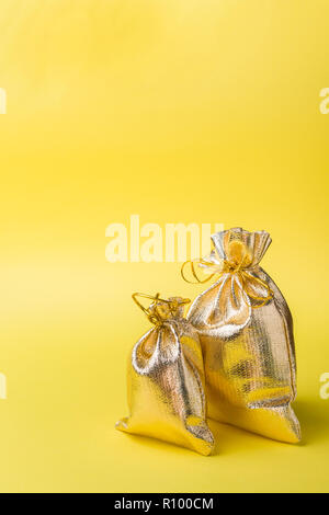 Christmas new year concept. Golden gift bag on a yellow background. Copy space. Stock Photo