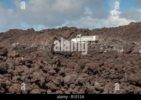 Pahoa, Hawaii - Trucks traverse a road being built on cooled lava from the 2018 eruption of the Kilauea volcano. This lava flow destroyed over 700 hom Stock Photo