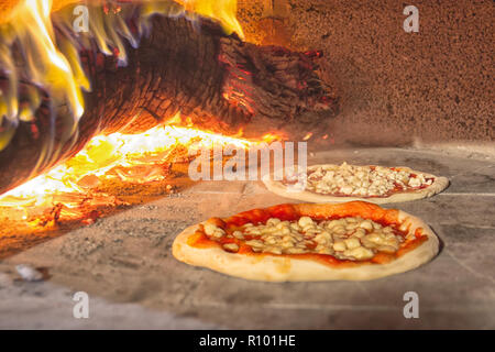 Pizzas in stone oven, with burning wood Stock Photo