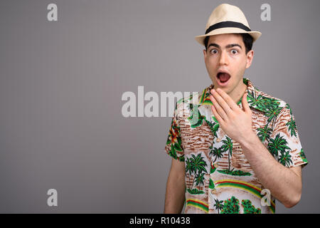 Young handsome tourist man ready for vacation against gray backg Stock Photo