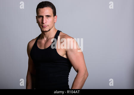 Studio shot of young muscular Persian man against gray backgroun Stock Photo