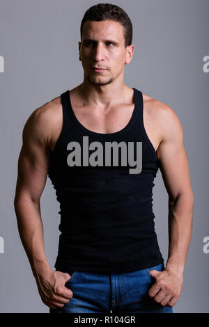 Studio shot of young muscular Persian man standing and thinking  Stock Photo