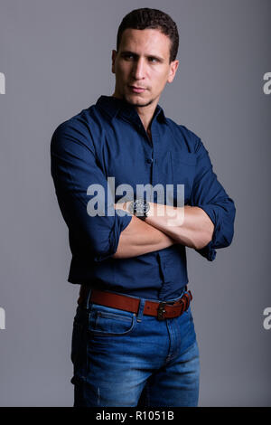 Studio shot of young muscular Persian man standing while thinkin Stock Photo