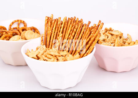Different salted crackers in bowls on white background. Stock Photo