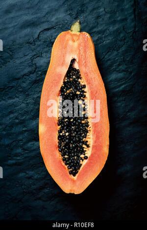 Papaya (Paw Paw) sliced in half and viewed from above on dark blue black slate rock Stock Photo