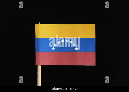 A official and original flag of Venezuela  on toothpick on black background. A horizontal tricolor of yellow, blue and red with an arc of eight white  Stock Photo