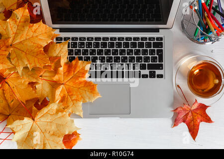 Girly office desktop with blank white laptop screen, flowers, coffee, smartphone and various office tools. Mock up Stock Photo