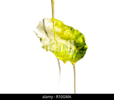 Oil pouring on floating lettuce leaf, white background Stock Photo