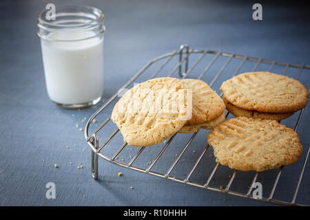 A close up of peanut butter cookies on a rack and a glass of milk. Stock Photo